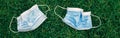 Two used sanitary masks lying on grass ground. Disposable recyclable face mask. Coronavirus, medicine and seasonal allergy. View