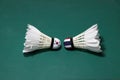 Two used shuttlecocks on green floor of Badminton court with both head each other. One head painted with South Korea flag And one