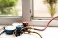 A two-valve manometric manifold lies on the windowsill in the apartment and measures the pressure in the air conditioner at home,