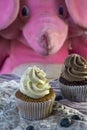 Two vanilla and chocolate cupcakes with blueberries and pink toy elephant Royalty Free Stock Photo