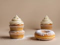 Two vanilla cupcakes with swirled frosting sit on a light brown background. Royalty Free Stock Photo