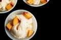 Two vanilla ice-cream with peach on black.