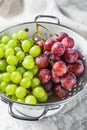 Two varieties of grapes, red and green in a colander. Gray background. Top view Royalty Free Stock Photo