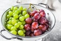 Two varieties of grapes, red and green in a colander. Gray background. Top view Royalty Free Stock Photo