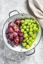 Two varieties of grapes, red and green in a colander. Gray background. Top view Royalty Free Stock Photo