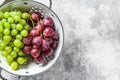 Two varieties of grapes, red and green in a colander. Gray background. Top view. Copy space Royalty Free Stock Photo