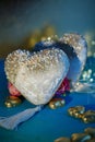 Two velvet white hearts with beads and golden foil chocolates on a blue table. Dark blurred background with bokeh Royalty Free Stock Photo