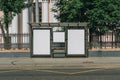 Two vertical blank white billboards at bus stop on city street. In the background buildings and trees. Mock up. Royalty Free Stock Photo