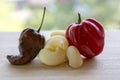 Two very hot habanero peppers, ripened habanero red and brown habanero chocolate, various mix of pasta on wooden table