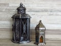 Two very old silver lanterns on bleached oak background.