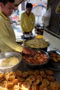 Two Vietnamese man making mini shrimp pancake on pavement at sidewalk restaurant, yellow crispy cake