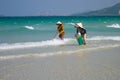 Two Vietnamese women are collecting sea shells on the shore in Nha Trang, Vietnam Royalty Free Stock Photo