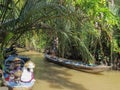 Two Vietnamese women have lunch sitting in a wooden boat. Standing on another boat and driving a paddle, a man moves