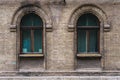 Two vintage arched windows in a wall of yellow bricks. Green - the colors of sea wave glass in a maroon dark red wooden Royalty Free Stock Photo