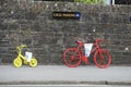 Two vintage bikes painted parked against the stone wall