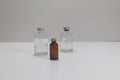 Two vintage clear vaccine bottles and one amber vaccine bottle, aged and patina on a white background