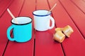 Two vintage coffee cups with cappuccino capsules on red wooden table Royalty Free Stock Photo