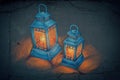Two vintage lanterns glowing softly on a textured dark surface, casting warm light and shadows Royalty Free Stock Photo
