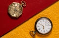 Two of vintage pocket watches lying on a books with red and yellow cover. Round dials of gold and silver retro watches Royalty Free Stock Photo