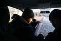 Two violent robbers sitting in a car looking at a blueprint of the building they want to rob