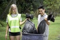 Two volunteers collecting trash garbage, holding and dumping garbage bag, clean up area of dirty, environmental charity concept Royalty Free Stock Photo