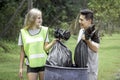 Two volunteers collecting trash garbage, holding and dumping garbage bag, clean up area of dirty, environmental charity concept Royalty Free Stock Photo