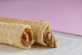 Two waffle cones with sweet boiled condensed milk in white plate on pastel pink background. Condensed tubules. Royalty Free Stock Photo