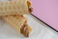 Two waffle cones with sweet boiled condensed milk in white plate on pastel pink background. Condensed tubules. Royalty Free Stock Photo