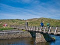 Two walkers cross the Three Quarter Mile wooden footbridge over the River Bush near Runkerry Beach on the Antrim Causeway Coast Royalty Free Stock Photo