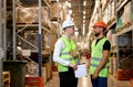 Two warehouse managers in work wear organizing distribution in warehouse storage area. Royalty Free Stock Photo