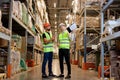 Two warehouse managers in work wear organizing distribution in warehouse storage area. Royalty Free Stock Photo