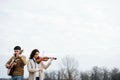 Two warmly dressed musicians playing in countryside at autumn over bright sky
