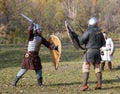 Two warriors in old Russian armors fight with swords and shields