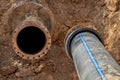 An old steel water pipe with a welded flange lies next to a new plastic pipe installed to connect the water supply