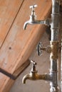 Two water taps mounted in zinc-coated water pipes reaching ot of facade of ruined house