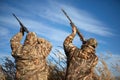 Two waterfowl hunters aiming into sky with guns Royalty Free Stock Photo