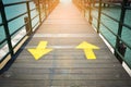 Two way yellow traffic arrows sign pointing to two direction on wooden bridge