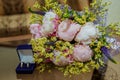 Two wedding rings are in a blue crust on the table and the bride`s bouquet of pink peonies. Royalty Free Stock Photo