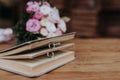 Two wedding rings in a book and wedding bouquet on table