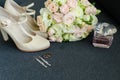 Two wedding rings, a bride's bouquet of roses, shoes, earrings, eau de parfum on a gray background. Bride details Royalty Free Stock Photo