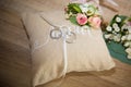 Two wedding rings on brown cushion rustic style close-up with flowers decoration