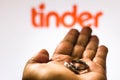 Two wedding rings on a mans hand and the Tinder logo on the bottom. People use Tinder for online dating