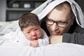 Two week newborn baby with father in bed