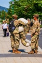 Two West Point Military Academy Cadets talking on campus. One is holding a stuffed bear in uniform unit mascot