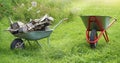 Two wheelbarrows with firewood on green lawn background Royalty Free Stock Photo