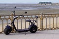 Two wheeled electric black scooter with large wide wheels on sea side