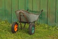 Two-wheeled garden trolley against a green wall