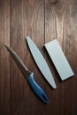 Two whetstones and steel knife, top view. Grindstones. Oval and rectangular double layer sharpening stone on wooden table Royalty Free Stock Photo