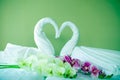 Two Whimsical Spa White Towel Origami Swans, Orchids, and Fake Flowers on bed Royalty Free Stock Photo