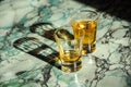 Two whiskey shots casting shadows on a marble surface in sunlight Royalty Free Stock Photo
